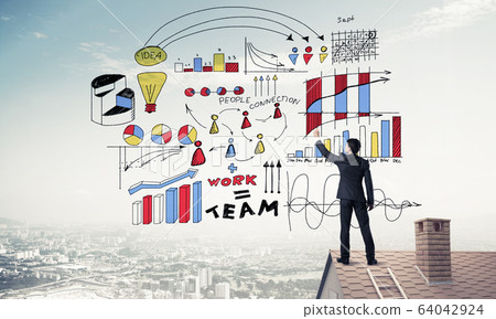 Rear view of businessman on house roof drawing his new business Rear view of businessman on house roof drawing his new business 64042924