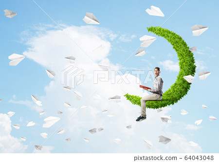 Handsome student guy sitting on green moon and reading book Handsome student guy sitting on green moon and reading book 64043048