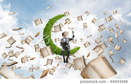 Young businessman or student studying the science and books flying around Young businessman or student studying the science and books flying around 64043086
