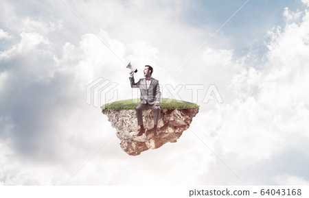 Businessman floating on island in sky and announcing something i 64043168