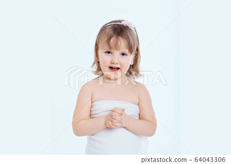 a little girl grimaces against a white background. The child is up to something. Concept of emotions , facial expressions, childhood, sincerity 64043306