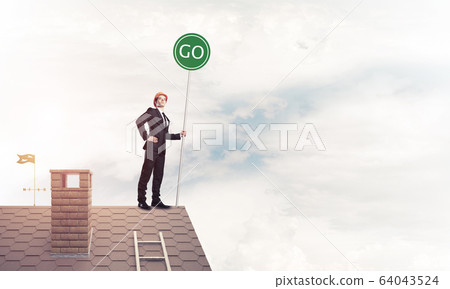 Businessman in suit on house top with ecology concept signboard. Businessman in suit on house top with ecology concept signboard. 64043524