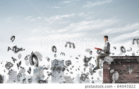 Man on roof edge reading book and symbols flying around Man on roof edge reading book and symbols flying around 64043822