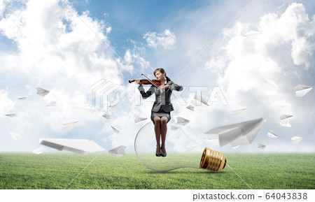 Young woman with violin sitting on glowing lamp 64043838