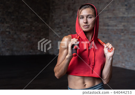 Attractive active young fit woman stand in gym hold jumping rope look at camera. Attractive active young fit woman stand in gym hold jumping rope look at camera. 64044253