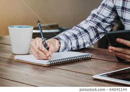 woman hand writing notepad and holding phone on 64045144