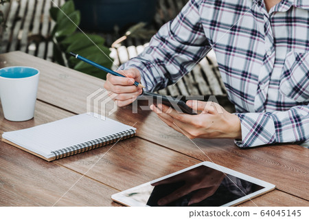 woman hand writing notepad and holding phone on 64045145