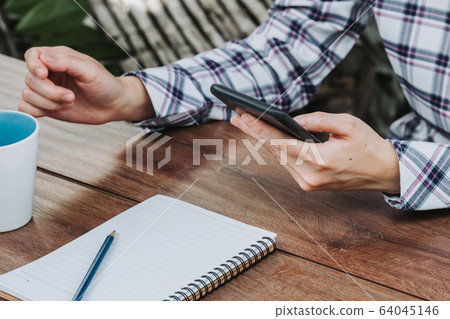 woman hand holding phone on wooden table 64045146
