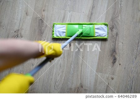 Male hand with yellow protective gloves hold green plastic mop Male hand with yellow protective gloves hold green plastic mop 64046289