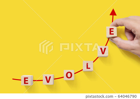 Wooded cube block on yellow background with word EVOLVE and copy space for your text 64046790