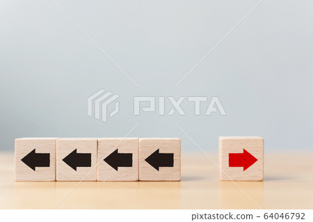 Hand holding wooden block with red arrow facing the opposite direction black arrows 64046792