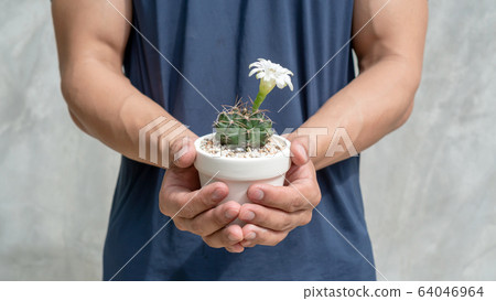 The man holds a pot to plant a cactus. The man holds a pot to plant a cactus. 64046964
