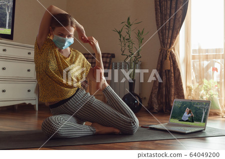 Sporty young woman taking yoga lessons online and practice at home while being quarantine Sporty young woman taking yoga lessons online and practice at home while being quarantine 64049200