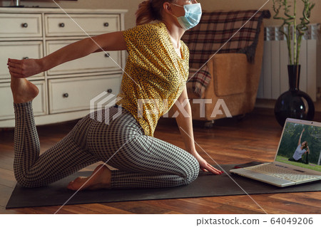 Sporty young woman taking yoga lessons online and practice at home while being quarantine 64049206