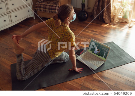 Sporty young woman taking yoga lessons online and practice at home while being quarantine 64049209