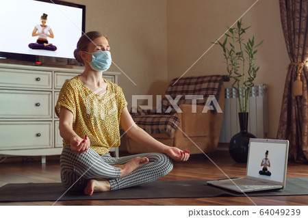 Sporty young woman taking yoga lessons online and practice at home while being quarantine 64049239