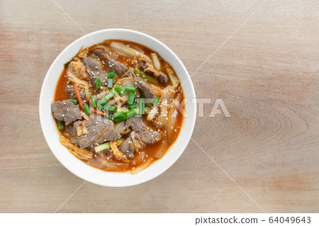 top view of stir fried beef with kimchi in a ceramic bowl on wooden table. top view of stir fried beef with kimchi in a ceramic bowl on wooden table. 64049643