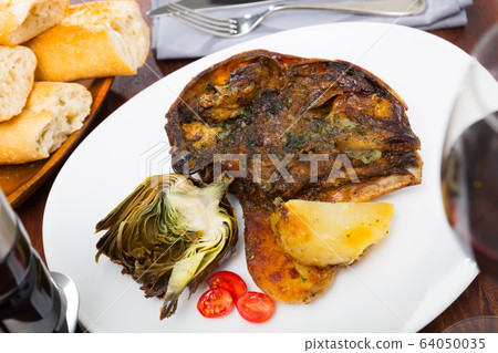 Cabeza de cordero - spanish dish. Lamb head with artichoke, tomatoes and potatoes 64050035