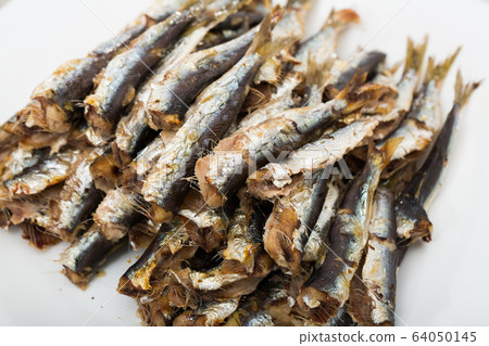 Deliciously cooked baked sprats served on white plate at table Deliciously cooked baked sprats served on white plate at table 64050145