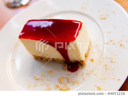 Slice of delicious classical cheesecake with fruity sauce served in cafeteria Slice of delicious classical cheesecake with fruity sauce served in cafeteria 64051216