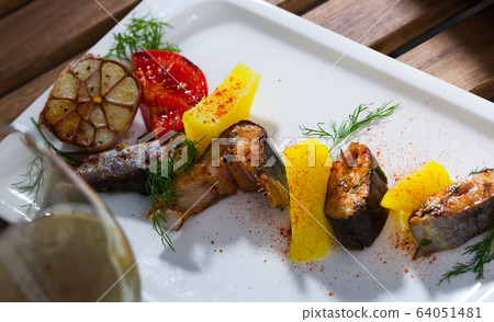 Baked trout steaks with potatoes, tomatoes, garlic and white wine 64051481