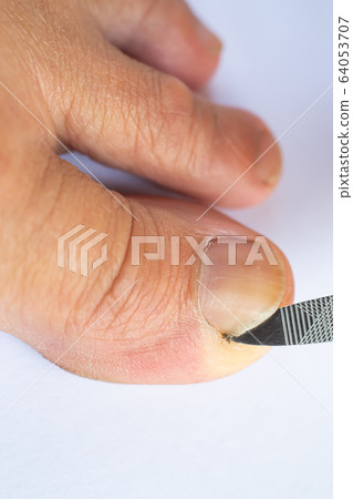 Female cleaning dirt from under toenails by nail file, Hygiene woman's foot, On white background, Close up & Macro shot, Selective focus, Asian body skin part, Healthcare concept 64053707