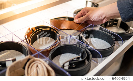 Male hand choosing leather belt in walk-in closet Male hand choosing leather belt in walk-in closet 64054964