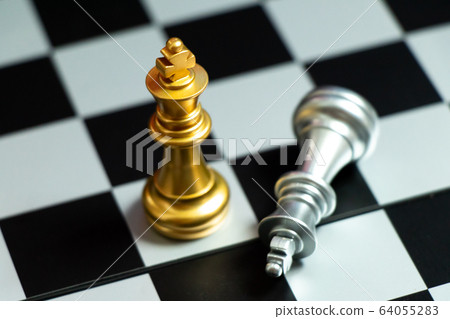 Top view of gold king chess piece win over lying down silver king on chess board background 64055283