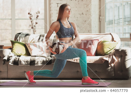 Young woman teaching at home online courses of fitness, aerobic, sporty lifestyle while being quarantine 64057770