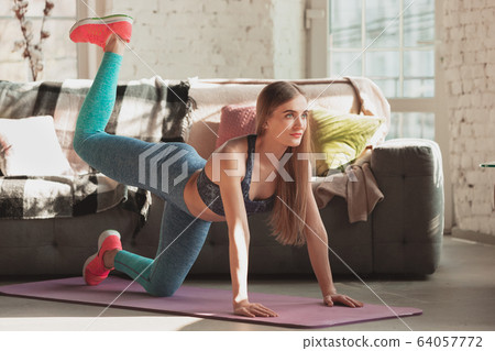 Young woman teaching at home online courses of fitness, aerobic, sporty lifestyle while being quarantine Young woman teaching at home online courses of fitness, aerobic, sporty lifestyle while being quarantine 64057772