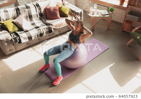 Young woman teaching at home online courses of fitness, aerobic, sporty lifestyle while being quarantine Young woman teaching at home online courses of fitness, aerobic, sporty lifestyle while being quarantine 64057923