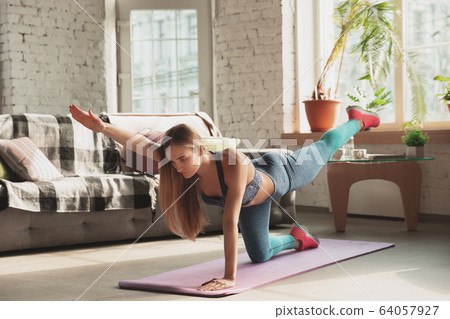 Young woman teaching at home online courses of fitness, aerobic, sporty lifestyle while being quarantine 64057927