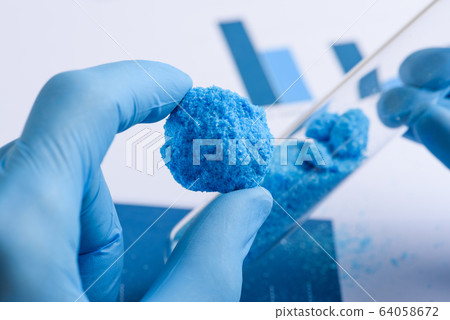 Researcher show big blue piece of crystal material in hand and glass test tube in laboratory 64058672