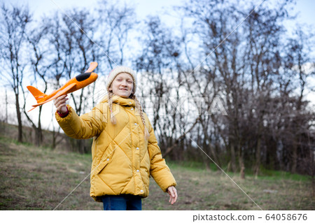girl plays with a toy airplane 64058676