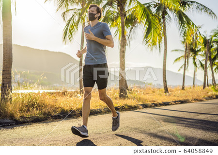 Runner wearing medical mask, Coronavirus pandemic Covid-19. Sport, Active life in quarantine Runner wearing medical mask, Coronavirus pandemic Covid-19. Sport, Active life in quarantine 64058849