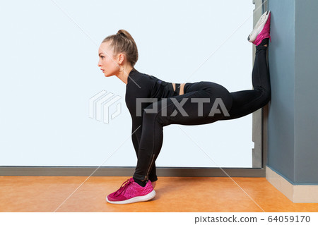 Woman doing the splits at wall 64059170