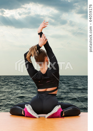 woman stretches by the sea 64059176