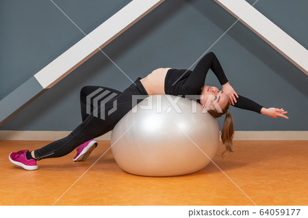 woman stretches herself on a ball 64059177