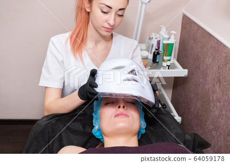 putting on a mask for light therapy 64059178