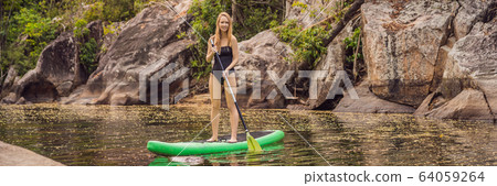 SUP Stand up paddle board woman paddle boarding on lake standing happy on paddleboard on blue water 64059264