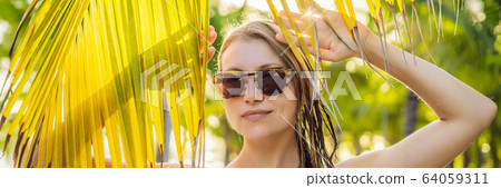 young beautiful woman in swimsuit on tropical beach, summer vacation, palm tree leaf, tanned skin 64059311