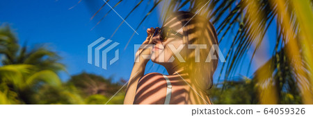 Young woman with the shadow of the palm leaf on her back. Relaxing on the seaside BANNER, LONG Young woman with the shadow of the palm leaf on her back. Relaxing on the seaside BANNER, LONG 64059326