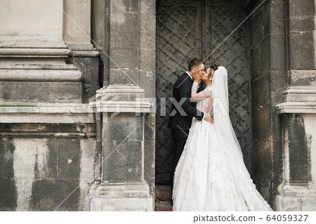 Lovely wedding couple kissing in the old city Lovely wedding couple kissing in the old city 64059327