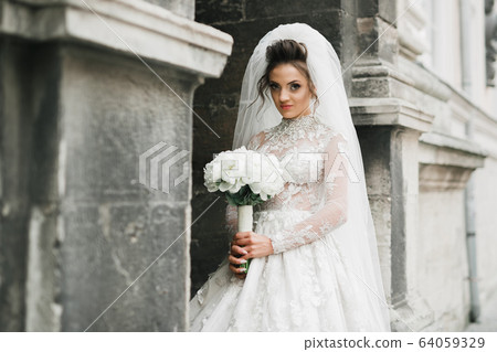 Portrait of stunning bride with long hair posing with great bouquet 64059329