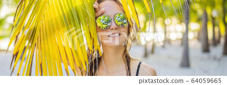 young beautiful woman in swimsuit on tropical beach, summer vacation, palm tree leaf, tanned skin 64059665