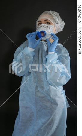 Young woman in protective clothing. On the face of a protective medical mask with a valve for eating. 64060886