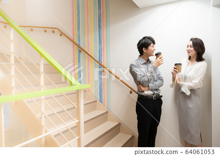 Young man and woman talking in office corridor Young man and woman talking in office corridor 64061053
