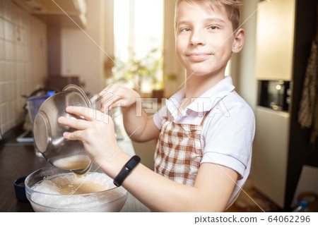 Small boy in the kitchen making tiramisu dessert 64062296