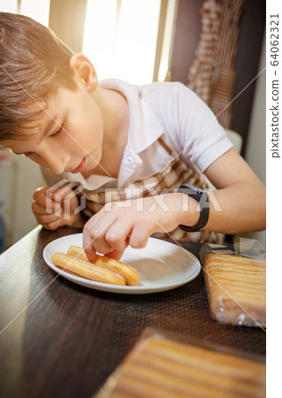 Fun boy stacking sweet cookies preparing tiramisu Fun boy stacking sweet cookies preparing tiramisu 64062321