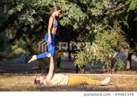 Young couple doing acroyoga exercises in park Young couple doing acroyoga exercises in park 64062349